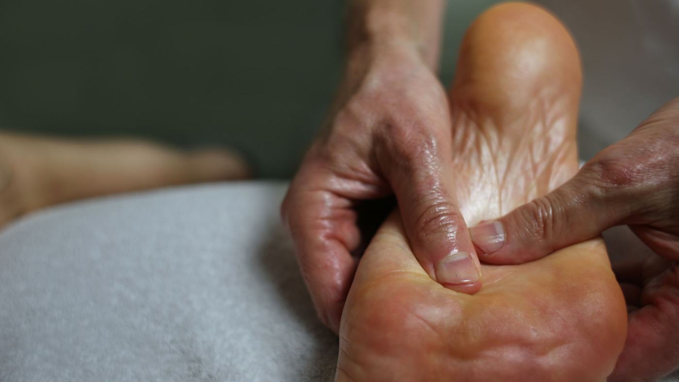 Massage van een voet op de behandeltafel tijdens een massage aan huis